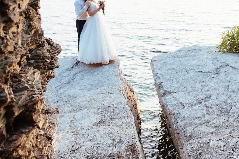 beautiful gorgeous blonde bride and stylish groom on rocks, on the background of a sea